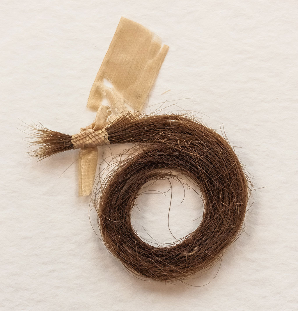 The stabilized lock of hair as viewed from the back: the backing textile and thread are much more visible here.