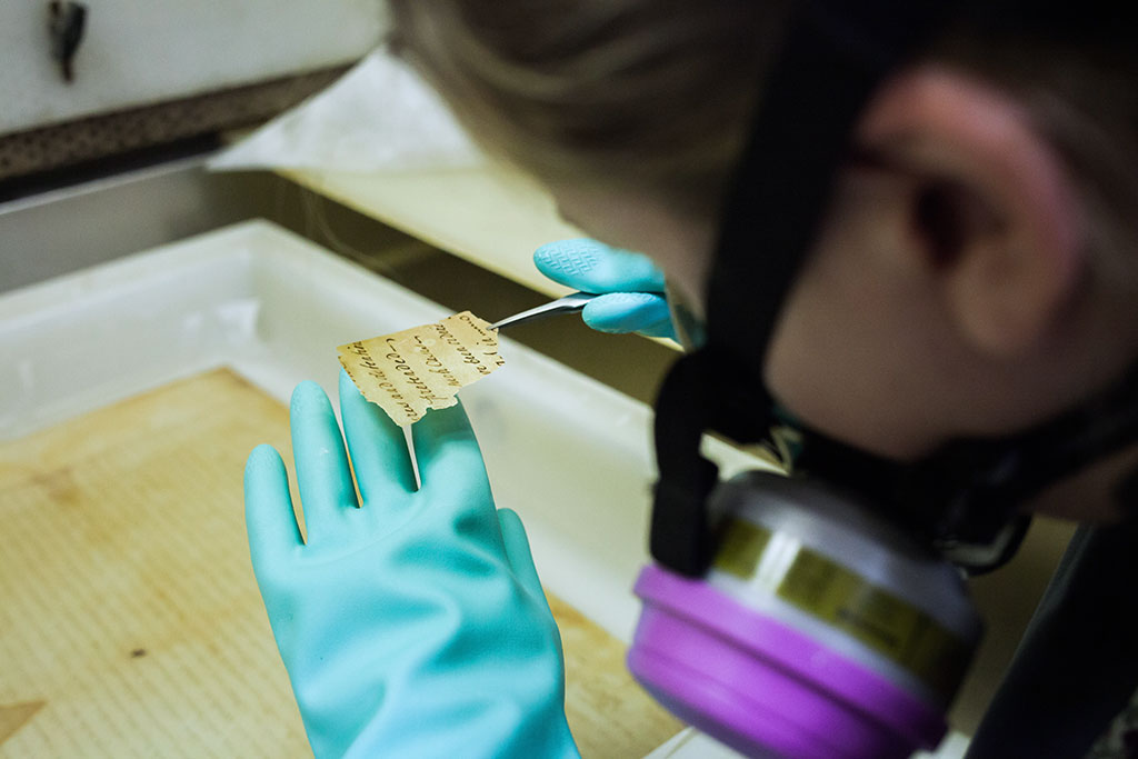 Conservator checking small fragment for adhesive haze